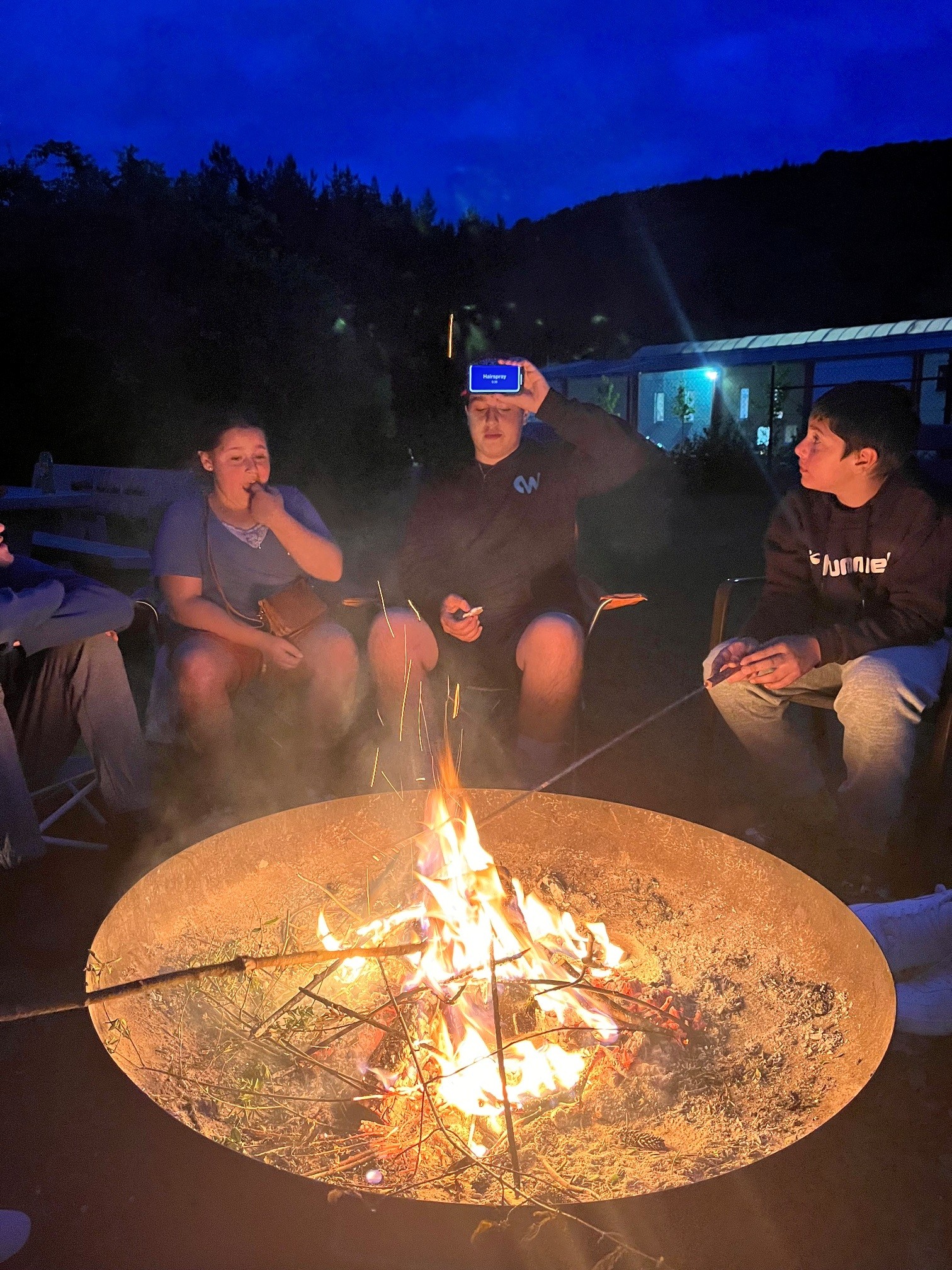 Friends gathered around a campfire at night